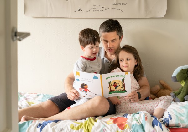 Father reading a book to his son and daughter.